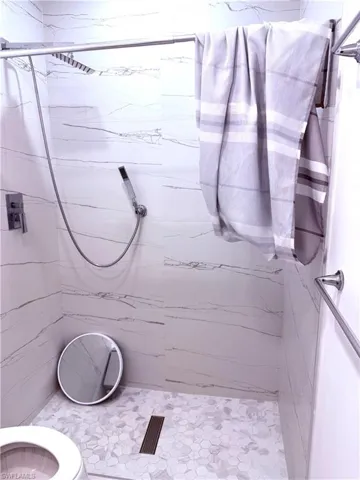 Bathroom featuring a marble finish shower and toilet