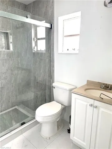 Full bath with vanity, a shower stall, and marble look tiles