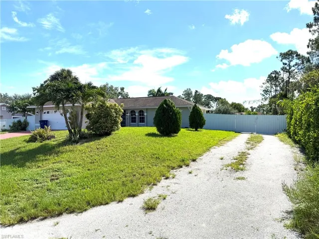 View of front facade featuring driveway, a gate, and stucco siding