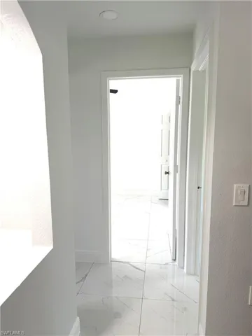 Corridor featuring baseboards and light marble finish floors