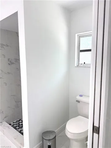 Bathroom featuring a shower stall and marble look tile flooring