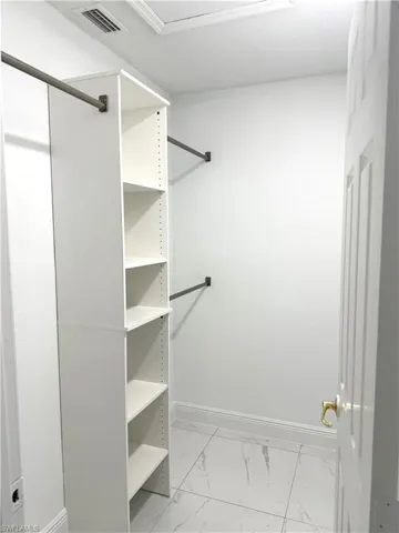 Spacious closet featuring light marble finish floors