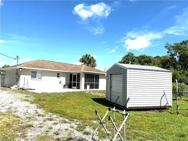 Back of property with a sunroom, a storage shed, and a lawn
