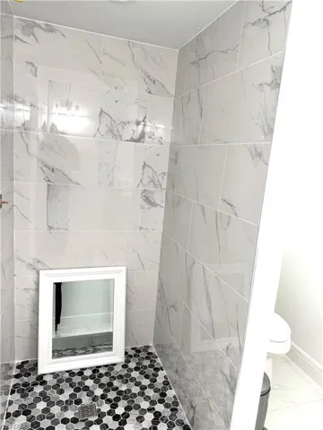 Bathroom with toilet and marble look tile flooring