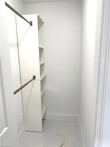 Walk in closet featuring light marble finish flooring