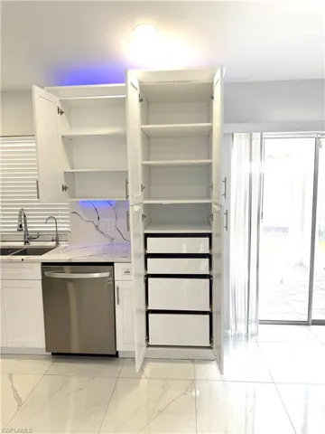Kitchen featuring open shelves, dishwasher, white cabinetry, and light marble finish flooring