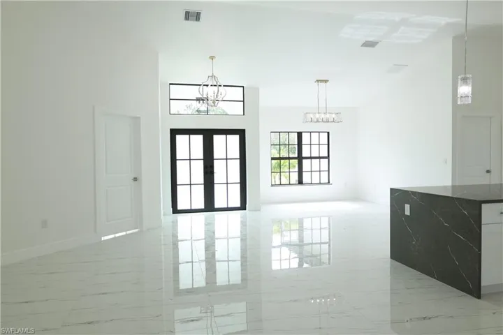 Kitchen featuring light marble finish flooring, dark stone countertops, white cabinets, and decorative backsplash