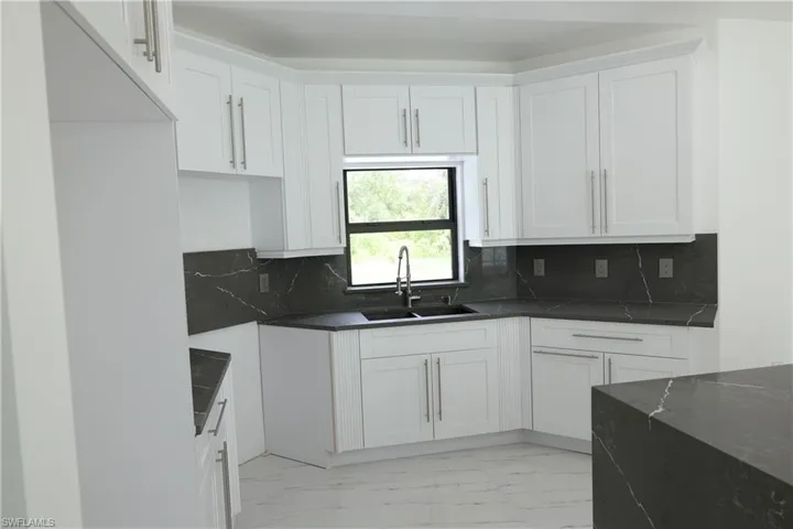 Kitchen with open floor plan, a chandelier, french doors, light marble finish floors, and a high ceiling