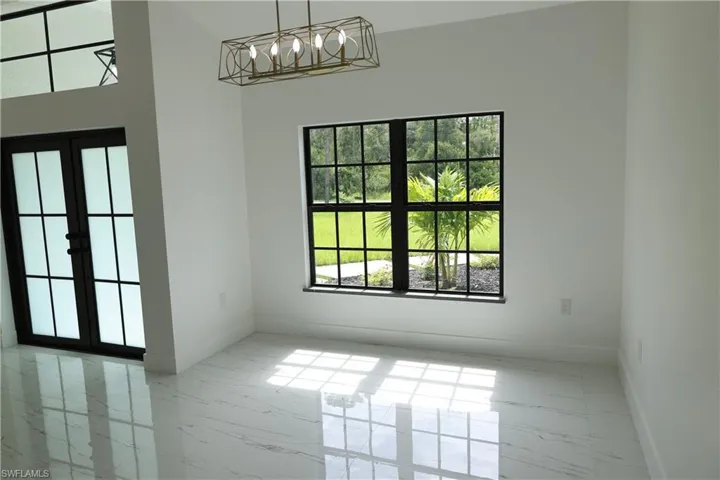 Dining space with french doors, a chandelier, plenty of natural light, marble look tiles, and a high ceiling
