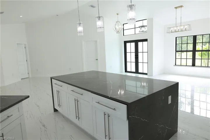 Kitchen featuring light marble finish floors, decorative backsplash, a spacious island, and white cabinetry