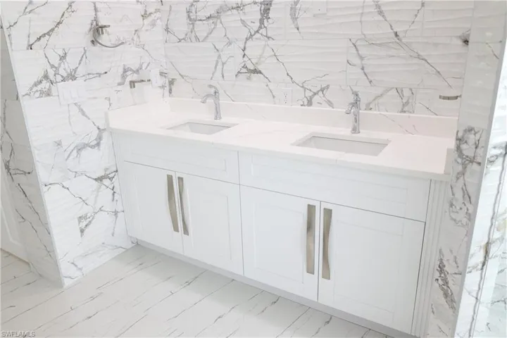 Bathroom with healthy amount of natural light, a marble finish shower, a freestanding tub, tile walls, and vanity