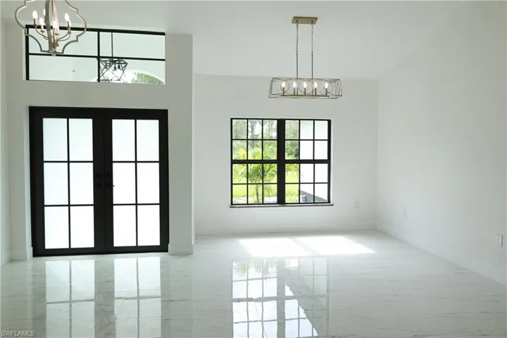 Spare room featuring marble tiled flooring and a chandelier