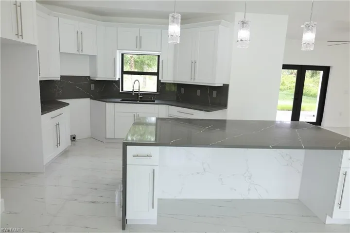 Kitchen featuring light marble finish flooring, decorative backsplash, a center island, and french doors