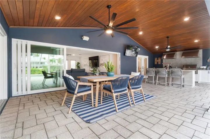 Outdoor covered Dining space with high vaulted ceiling and wooden clad plank ceiling stained to match soffits.