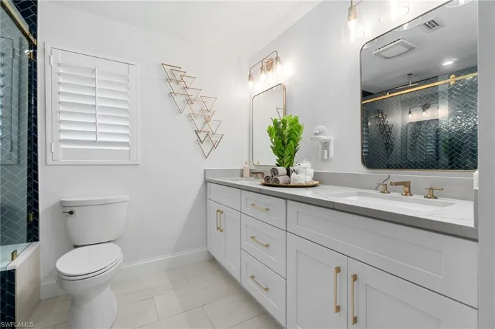 Owner’s Bathroom with double sink custom shaker vanity w/quartz top, tile patterned floors, and  with a frameless glass enclosed shower.