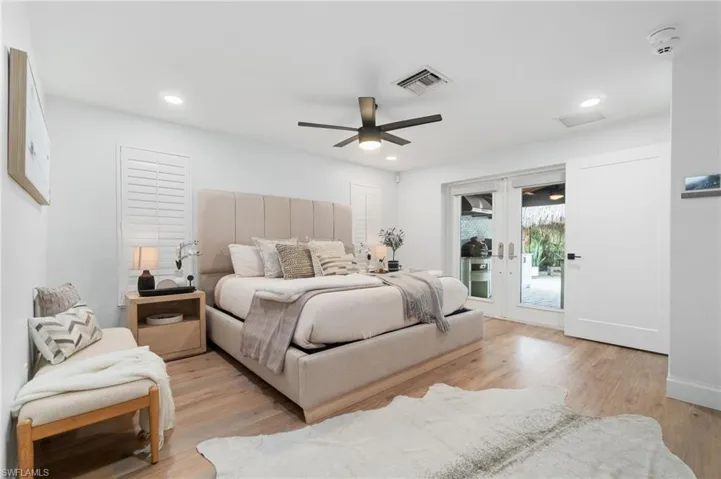 Primary Bedroom featuring new ceiling fan, French door access to covered rear entertainment area, and light oak LVP flooring.