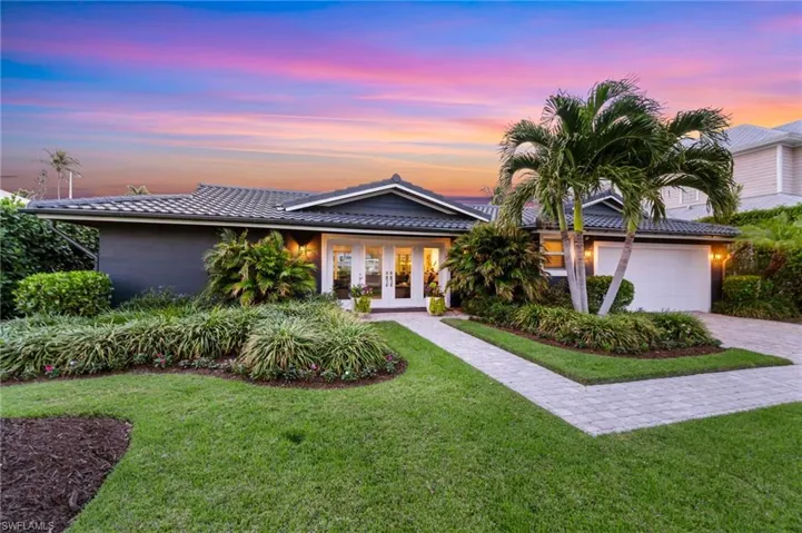 View of front of home with french doors, a garage, and a lawn