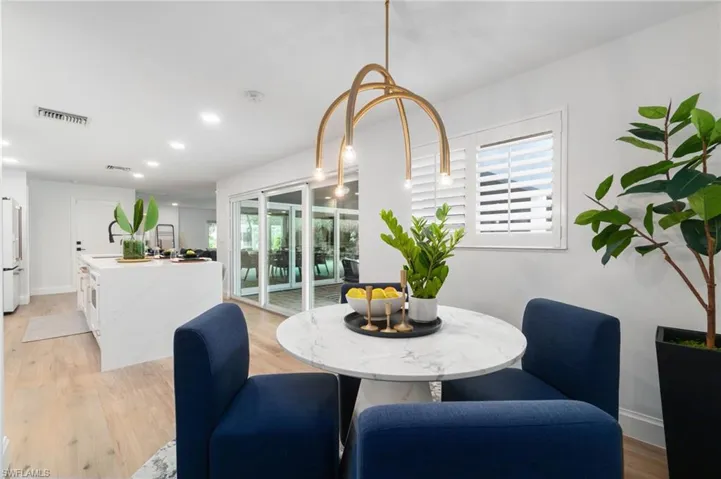 Dining space featuring light brand new designer chandelier set off from the kitchen.