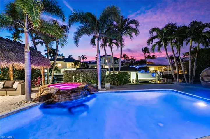 Pool at dusk featuring an in ground hot tub and water feature waterfall.