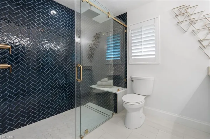 Primary Bathroom ensuite featuring an enclosed navy subway tiled shower with designer gold fixtures.