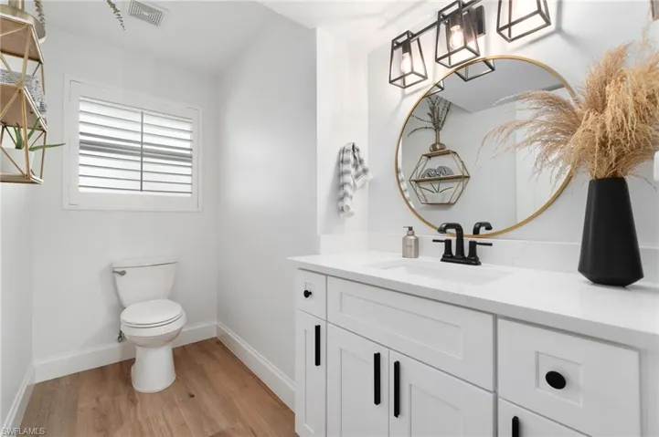 1/2 guest bath featuring new LVP white oak flooring, new quartz shaker vanity, and toilet
