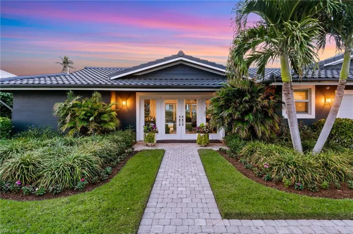 View of front of home with a yard and french doors