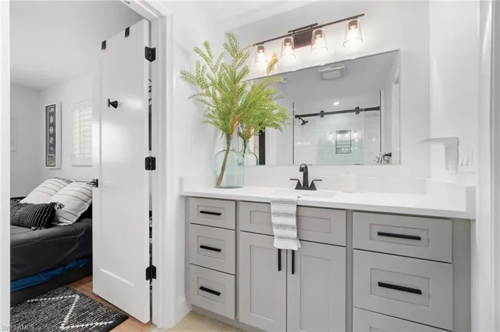 Bathroom with NEW LVP flooring , grey shaker quartz top vanity, and a custom tiled modern shower with frameless black matte hard-wear glass shower door.