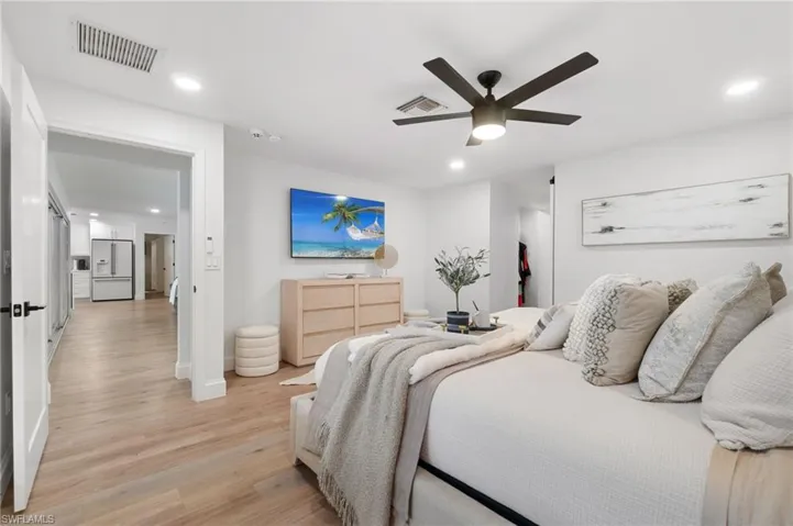 Owner’s Bedroom ensuite with upgraded ceiling fan, bright and airy paint, cohesive wood look plank tile flooring and a French door access to the pool.