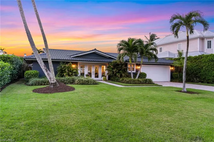 Single story modern coastal ranch style home featuring double french door entry, a landscaped tropical front and backyard, and a 2 car garage with laundry, custom storage and epoxy floors.