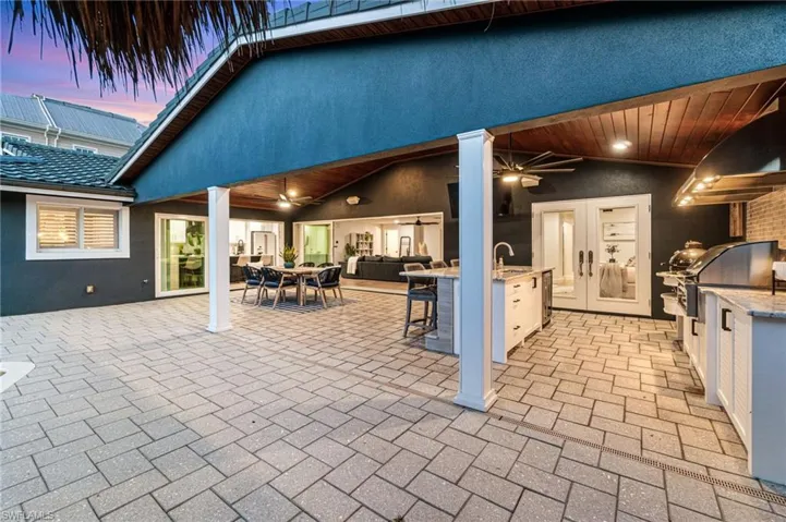 Patio terrace at dusk featuring ceiling fan, exterior kitchen, and sink