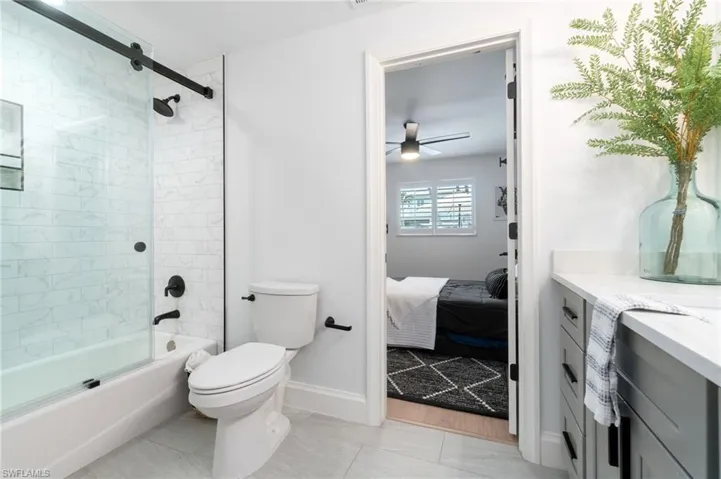 2nd Full bathroom is connecting to both guest bedrooms with upgraded vanity, tiled shower / bath combo with frameless glass door, ceiling fan, toilet, and matte black fixtures and faucets.