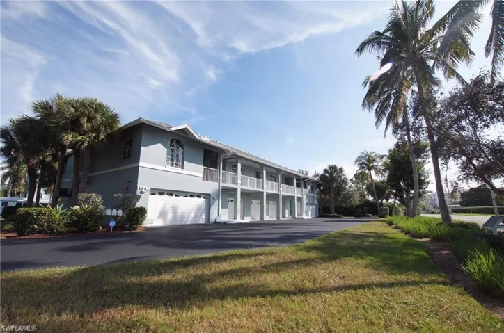 View of front of house with a front yard, a garage, and a balcony