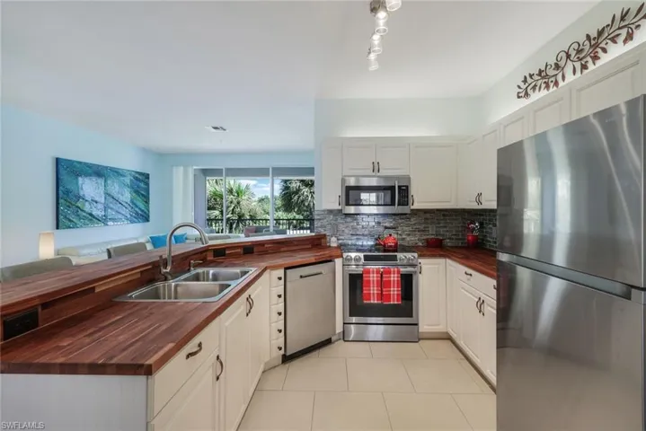 Kitchen featuring wood counters, white cabinets, stainless steel appliances, and sink