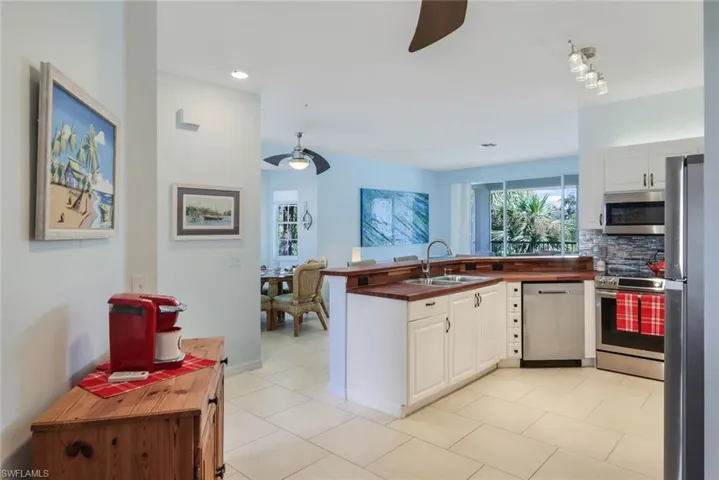 Kitchen featuring stainless steel appliances, sink, light tile patterned flooring, and white cabinets