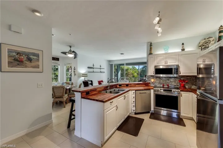 Kitchen featuring ceiling fan, stainless steel appliances, kitchen peninsula, and white cabinetry