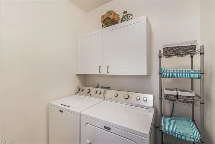 Washroom featuring cabinets and washing machine and clothes dryer