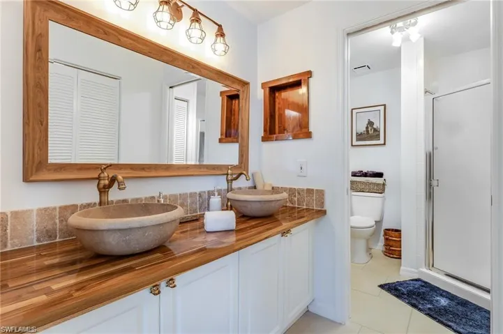 Bathroom with tile patterned floors, a shower with door, vanity, and toilet