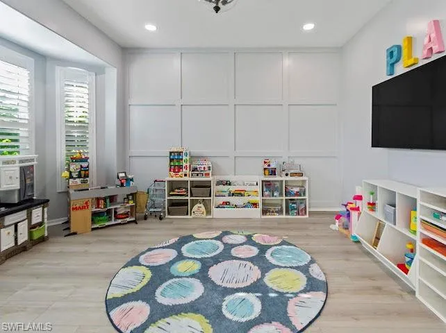 Recreation room with light wood finished floors and recessed lighting