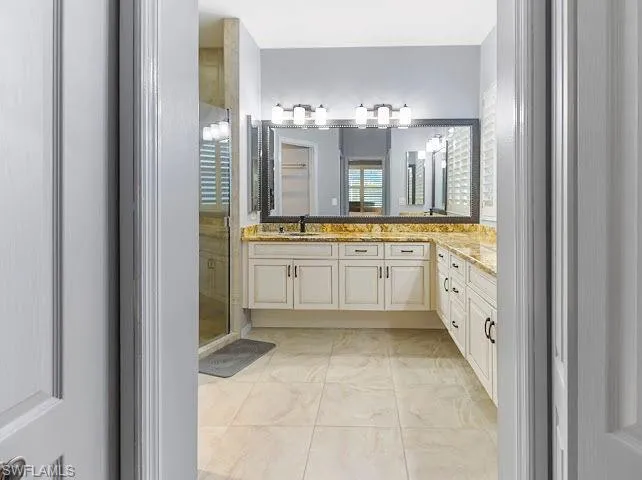 Bathroom featuring vanity, light tile patterned floors, and a stall shower
