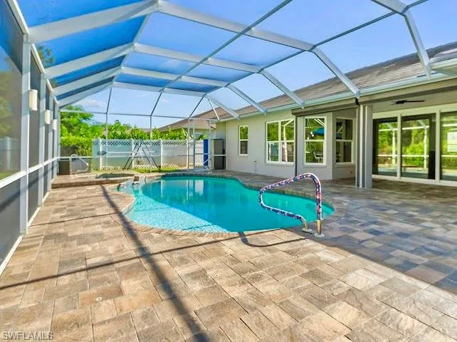 View of swimming pool featuring a sunroom, glass enclosure, a patio, a pool with connected hot tub, and ceiling fan