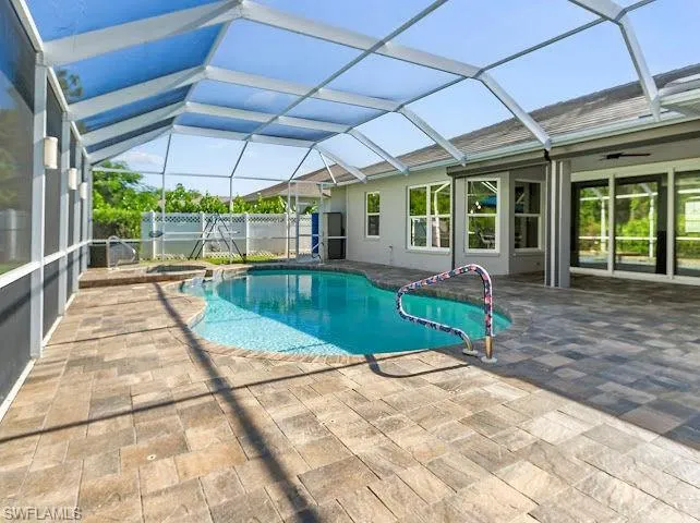 View of pool featuring a sunroom, a lanai, a patio, a pool with connected hot tub, and ceiling fan