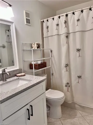 Bathroom with tile flooring, a shower with curtain, vanity, and toilet