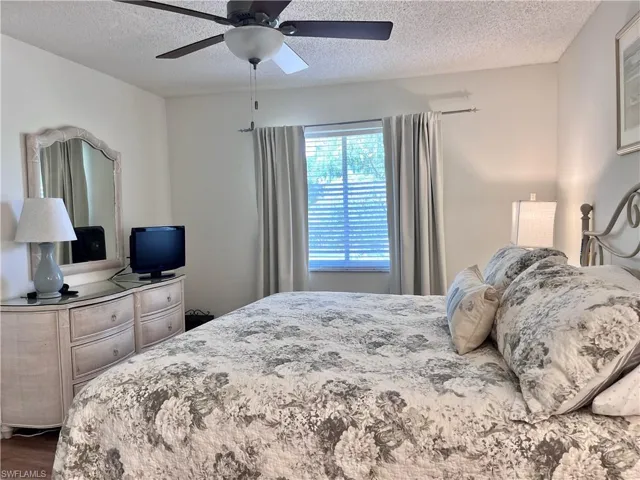 Bedroom featuring ceiling fan, a textured ceiling, and dark wood-type flooring