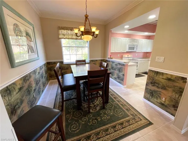 Dining area with a notable chandelier, ornamental molding, and light tile patterned floors