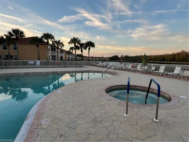 Pool at dusk featuring a hot tub and a patio
