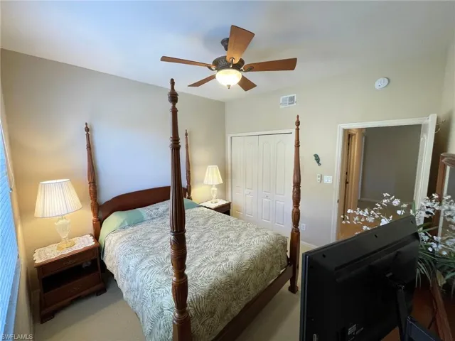 Carpeted bedroom featuring ceiling fan and a closet