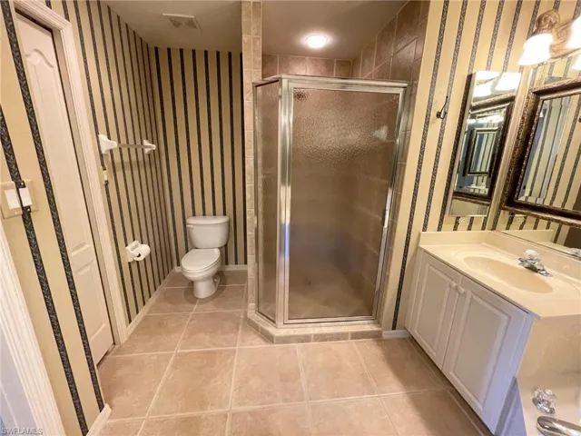 Bathroom with walk in shower, tile patterned floors, toilet, and vanity