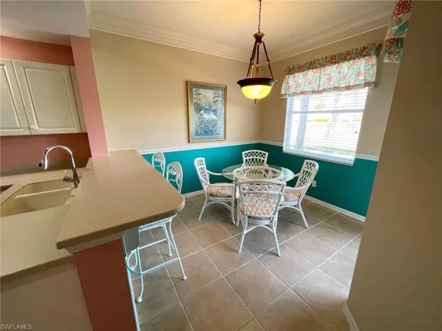 Tiled dining space featuring sink and ornamental molding