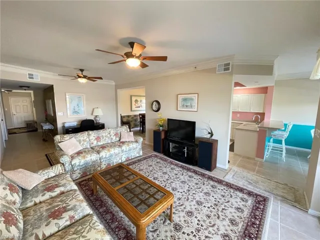 Tiled living room with ceiling fan, ornamental molding, and sink