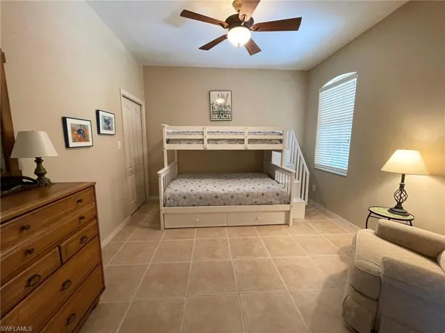 Bedroom with ceiling fan, a closet, and light tile patterned floors
